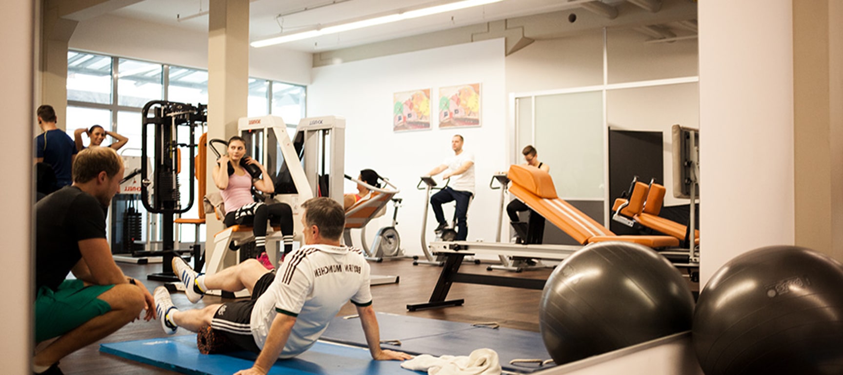 Bild mit dem PHYSICS Trainingsraum und Sportler die an den Geräten trainieren